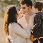 Family sharing affectionate moments outdoors with parents and child enjoying the sunny day.
